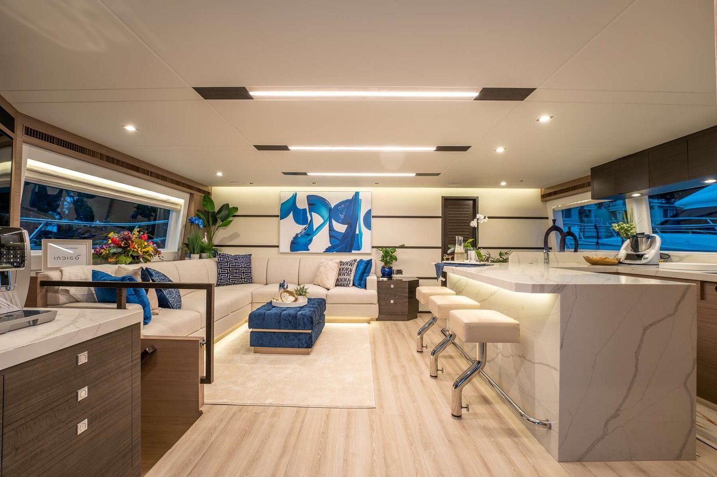 Indigo's main salon — cream sofas, marble galley bar, and indigo-blue accents